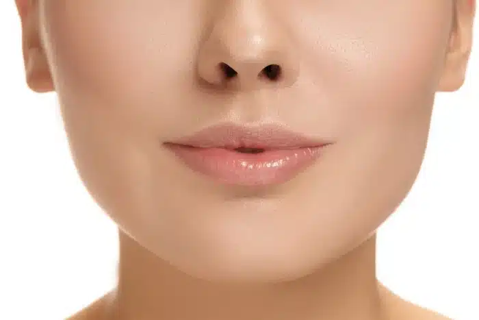 Close-up of a woman's lower face showing smooth skin and natural, slightly smiling lips.