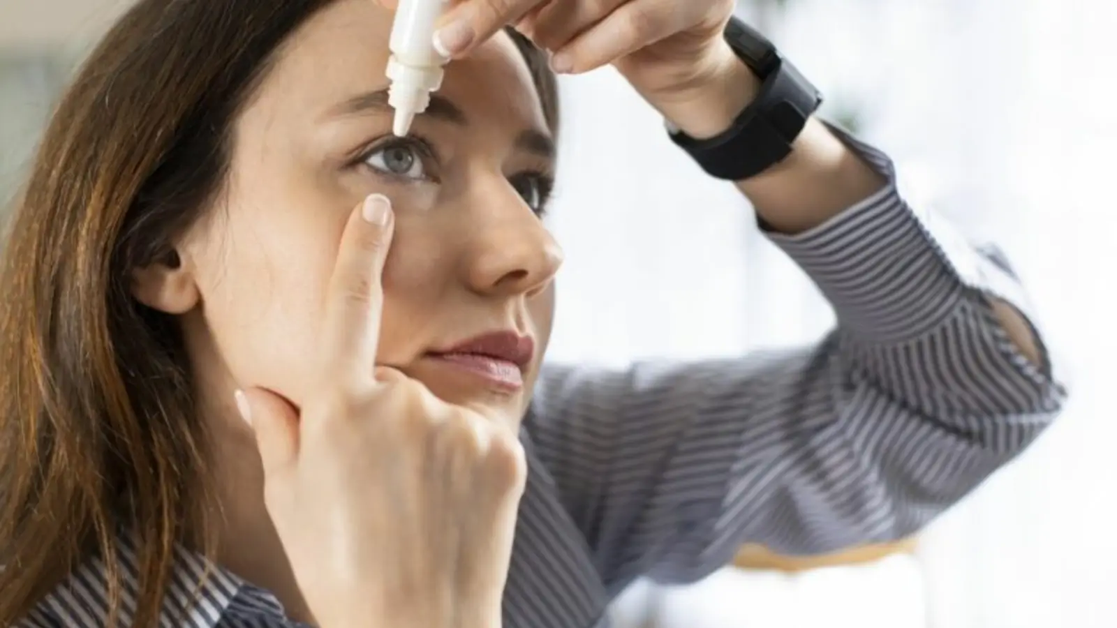 Person putting drops in her eyes.