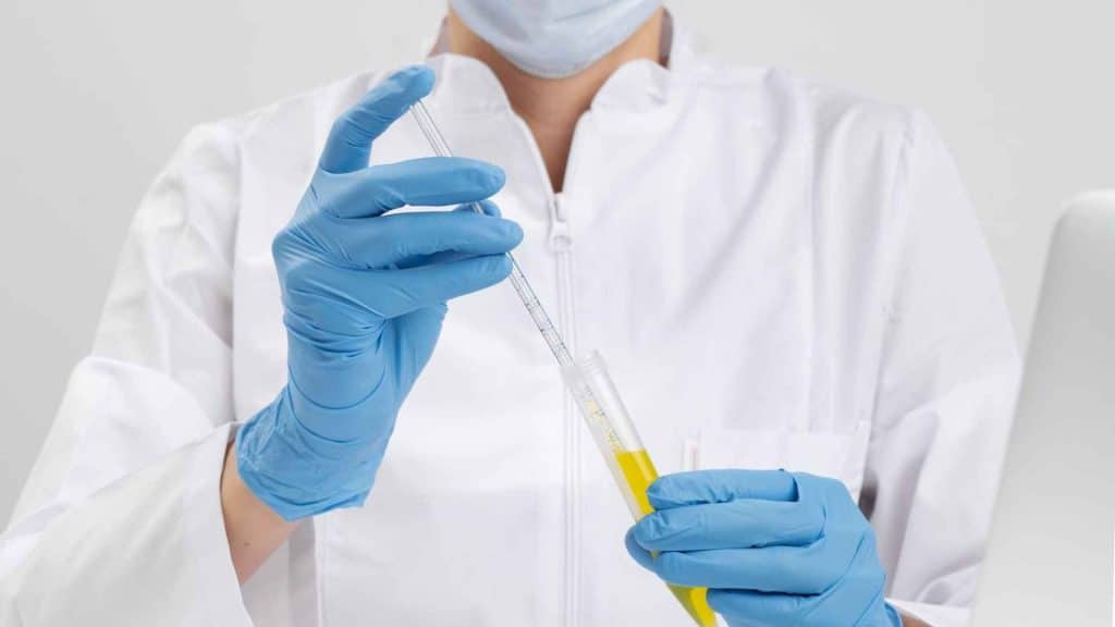 Close-up of a scientist measuring sterile liquid with a syringe beside labeled research vials