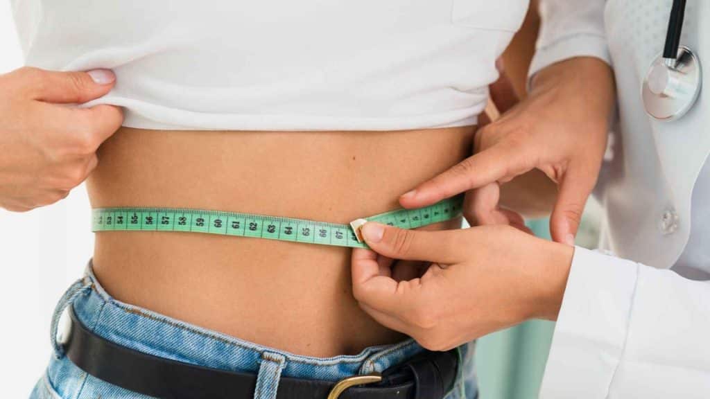 Healthcare professional measuring an adult participant’s waist circumference during a metabolic clinical trial
